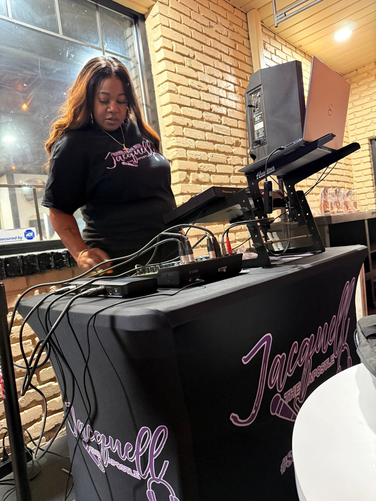 Jacquell The Apostle DJing at an evening event in a brick room