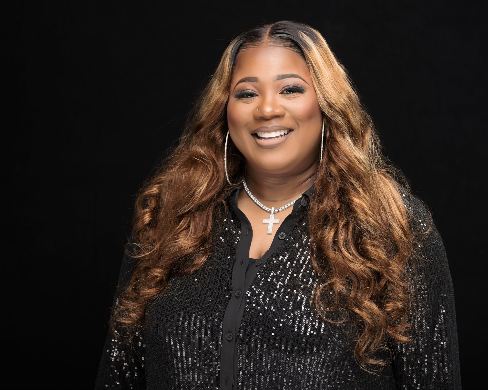 Jacquell The Apostle smiling in a black sequin top