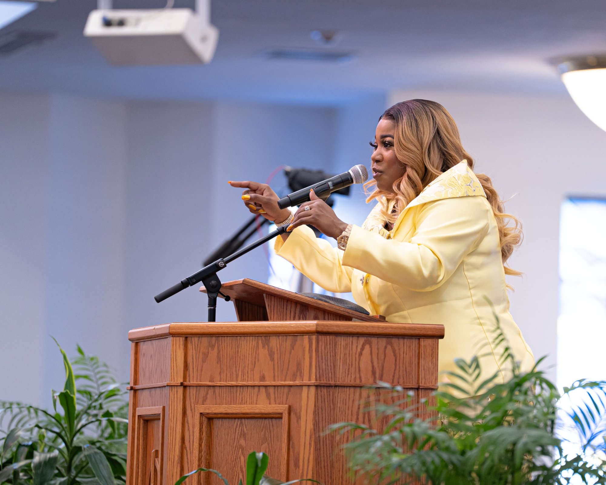 Jacquell The Apostle preaching at a pulpit in a yellow suit, pointing at the crowd